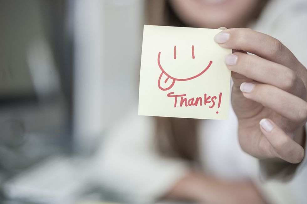 close up of woman holding a sticky note with a smiley face