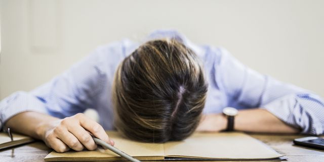 Close-up of woman lying on notebook at desk