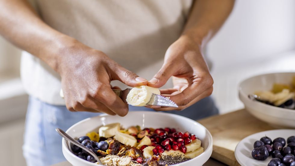 close up of woman making healthy breakfast in kitchen with fruits and yogurt