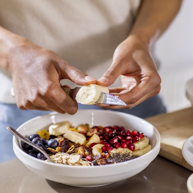 close up of woman making healthy breakfast in kitchen with fruits and yogurt