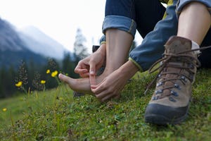 Close-up of woman putting band aid on foot after hiking