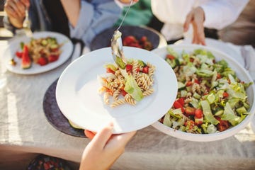 iemand schept een bord met pastasalade op