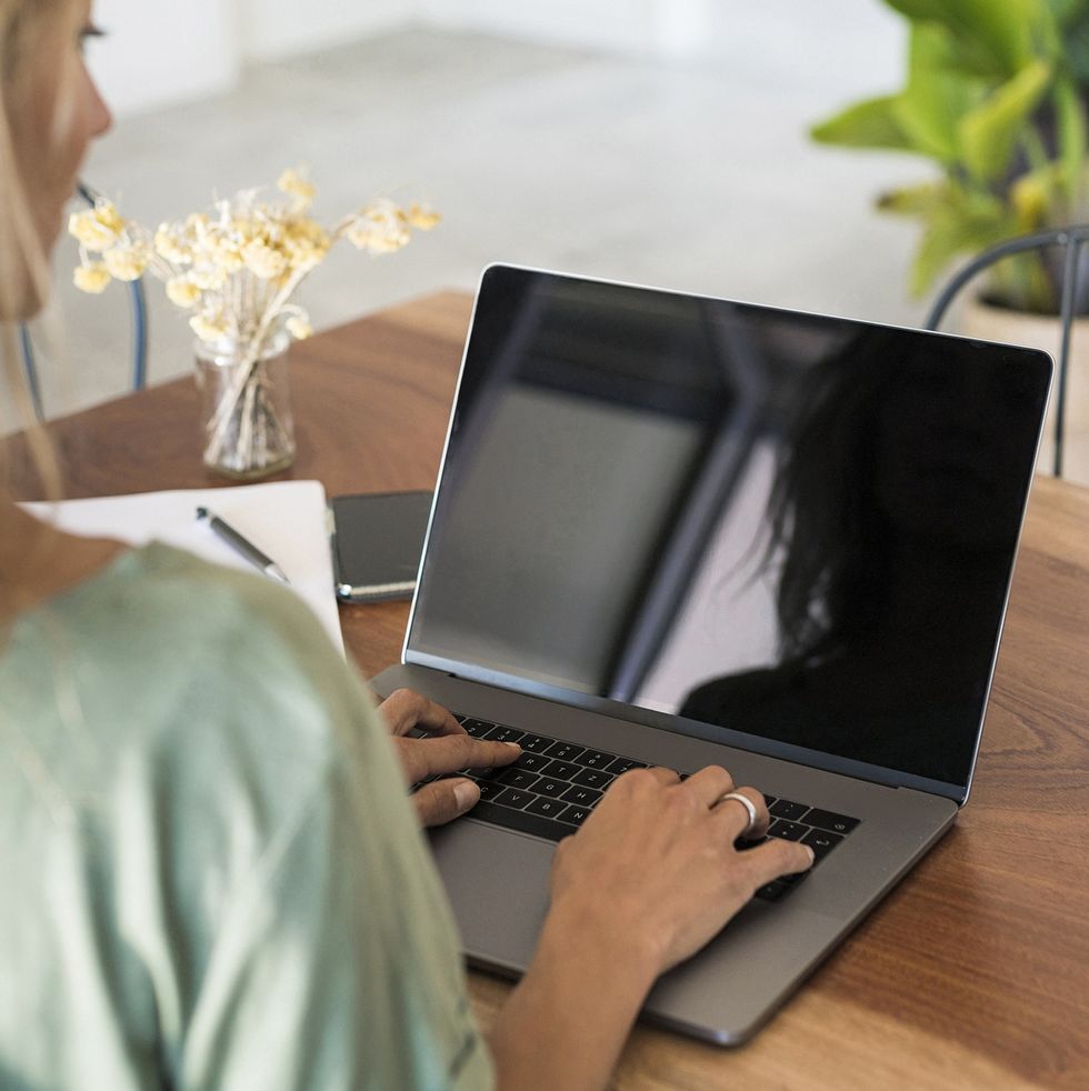 close up of woman using laptop on wooden table at home