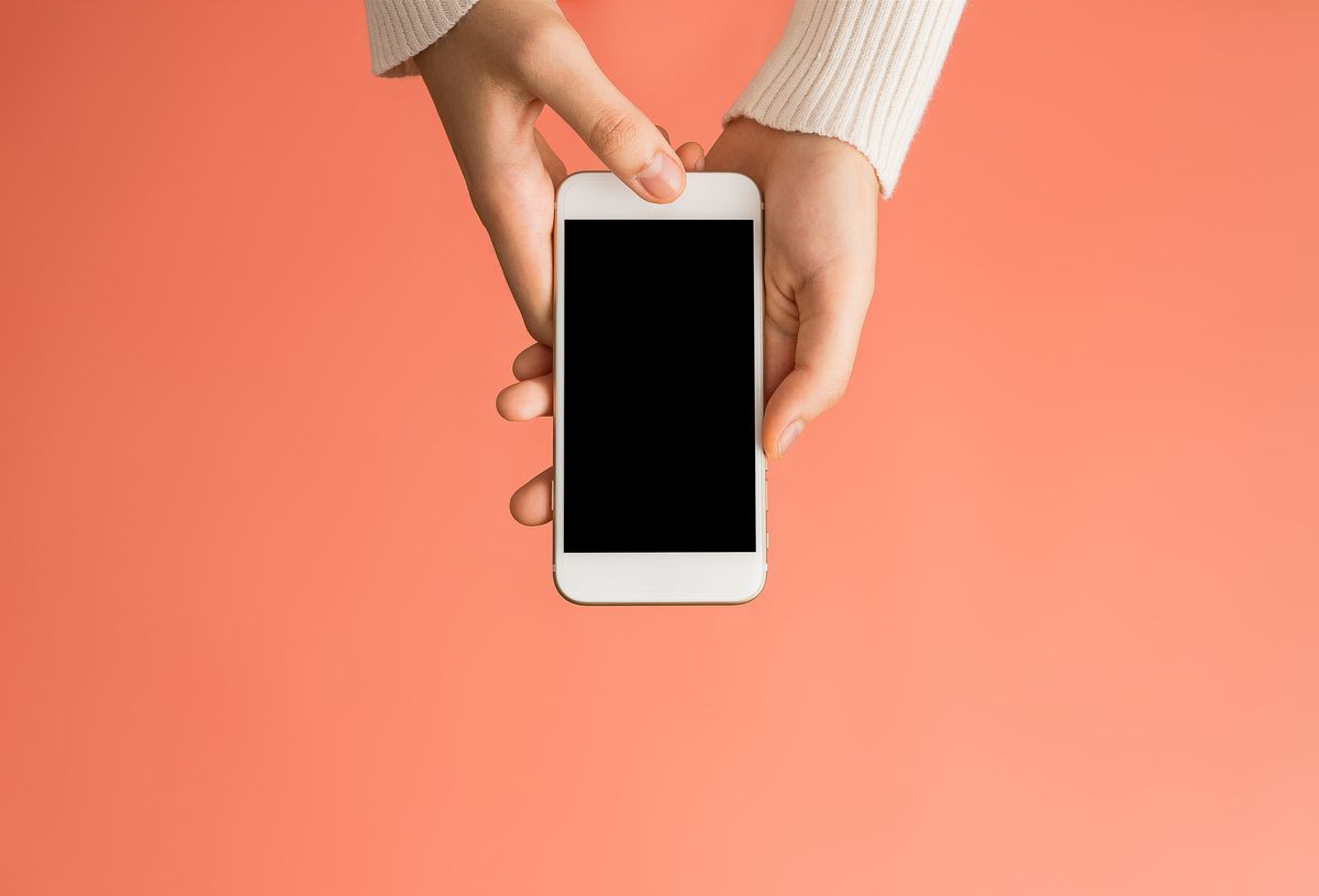 close up of woman using mobile phone over pink background