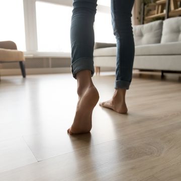 close up of woman walking barefoot on warm wooden floor