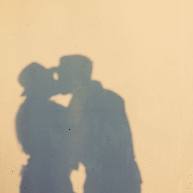close up of woman with shadow of couple kissing on wall