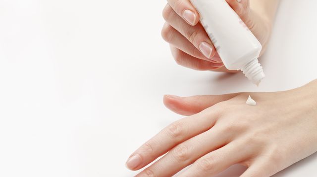 Close up of woman's hands applying  moisturizer, studio shot
