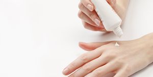 Close up of woman's hands applying  moisturizer, studio shot