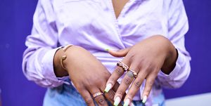 close up of woman's hands with lots of gold rings and painted nails