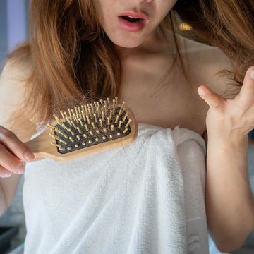 close up of worried woman holding comb with hair loss after brushing her hair