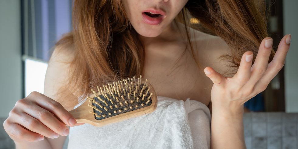 close up of worried woman holding comb with hair loss after brushing her hair
