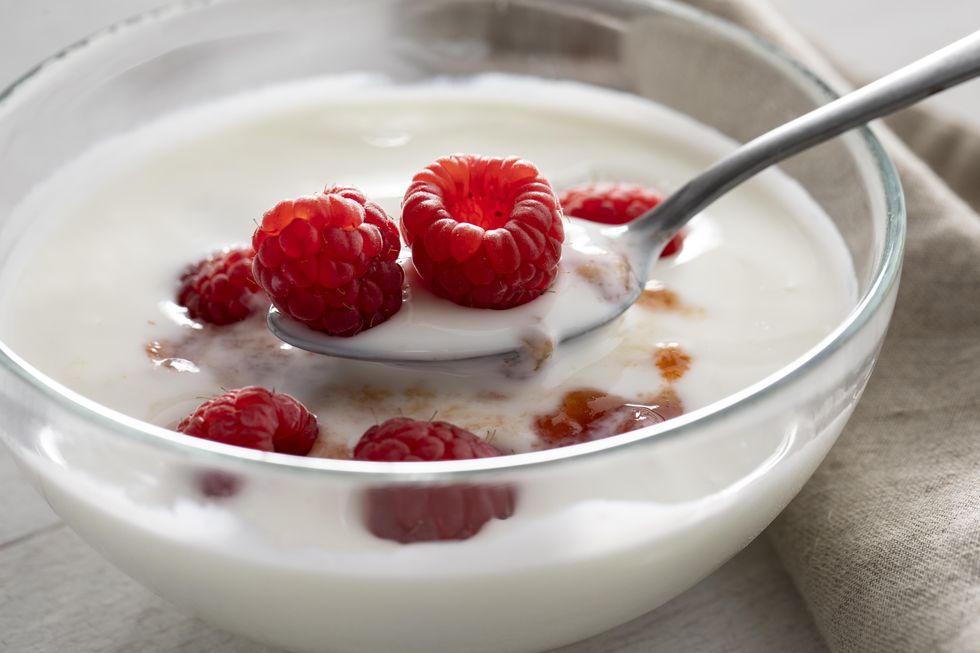 close up of yogurt with raspberries in bowl on table