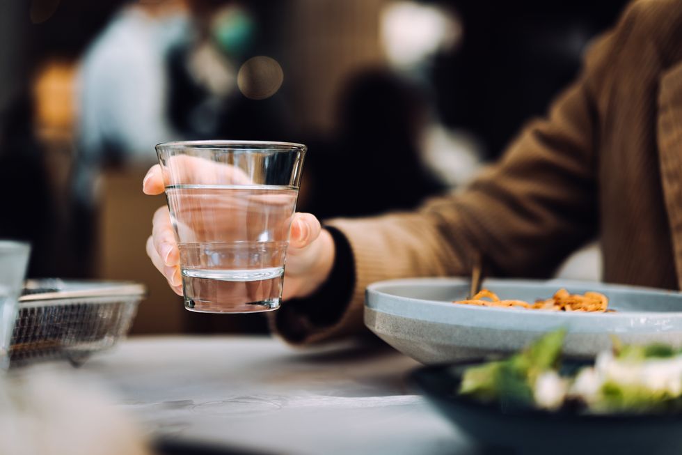 close up of young asian woman drinking a glass of water while having meal in a restaurant healthy lifestyle and stay hydrated