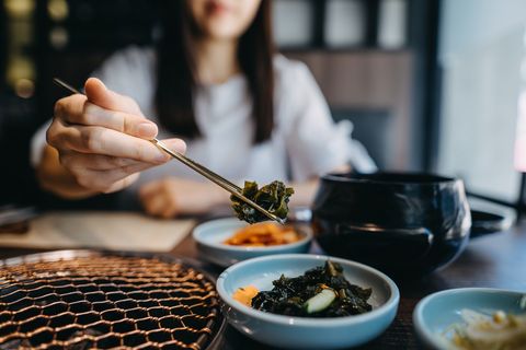 close up of young asian woman eating korean appetitizer seaweed while having meal in a korean restaurant