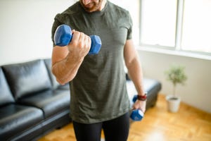 deportista entrenando con dos mancuernas en casa