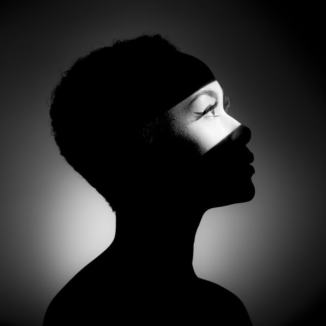 close up of young woman in light against black background