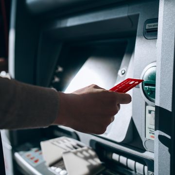 close up of young woman inserting her bank card into automatic cash machine in the city withdrawing money, paying bills, checking account balances, transferring money privacy protection, internet and mobile security concept