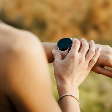 close up of young woman setting her smart watch before jogging in nature