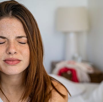 close up of young woman with headache sitting on bed