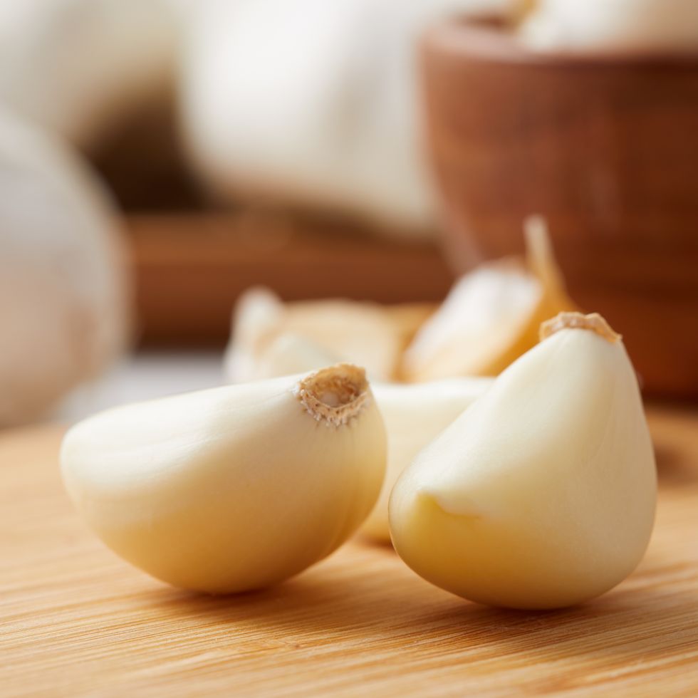 close up on a clove of garlic and garlic bulbs