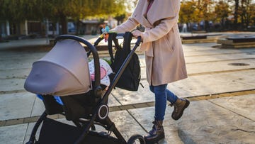 close up on midsection of unknown caucasian woman mother pushing stroller with baby in the city in day motherhood concept