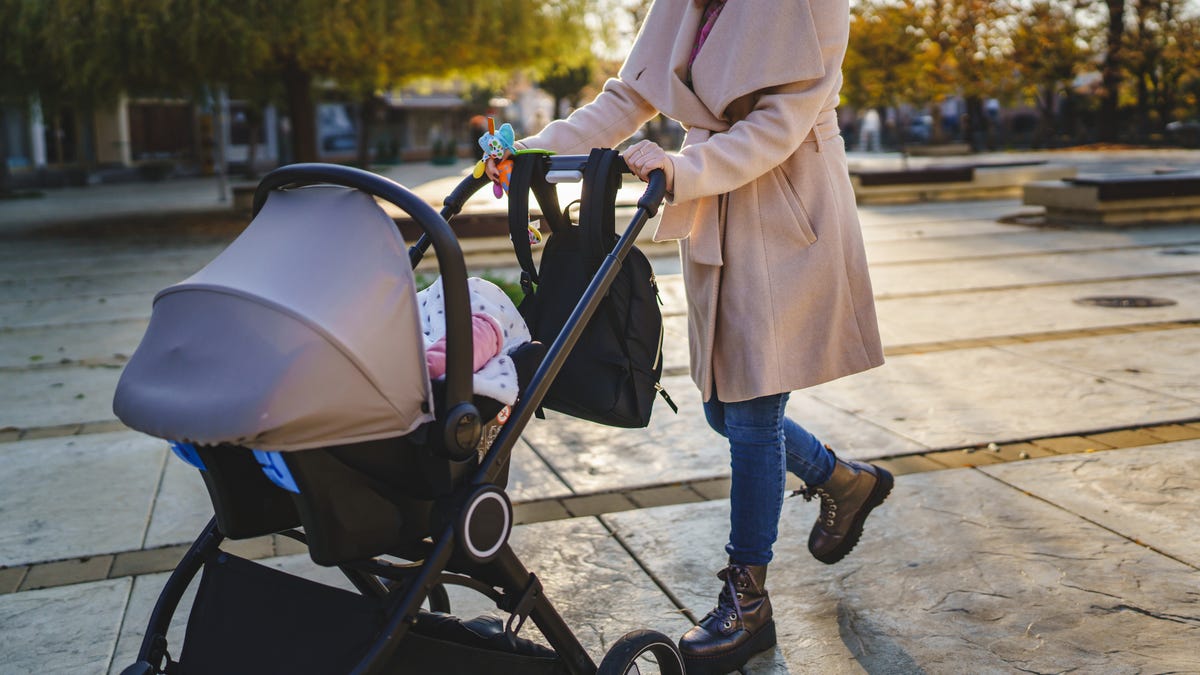 close up on midsection of unknown caucasian woman mother pushing stroller with baby in the city in day motherhood concept