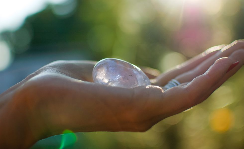 close up photo of female hand with transparent amethyst yoni egg for vumbuilding quartz crystal egg in hands on sunset background womens health concept