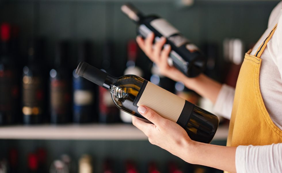 close up photo of woman hands holding two bottles of wine