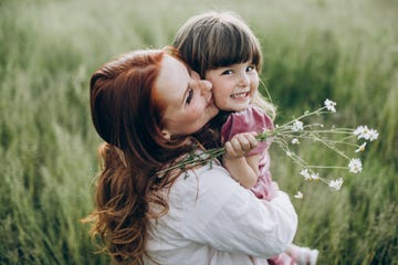 nina con madre en el campo con flores en la mano