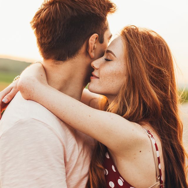 close up portrait of a caucasian young loving couple embracing while standing on a roadside couple embracing road travel sunset scene
