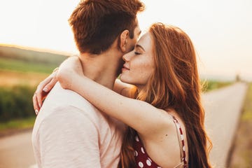 close up portrait of a caucasian young loving couple embracing while standing on a roadside couple embracing road travel sunset scene