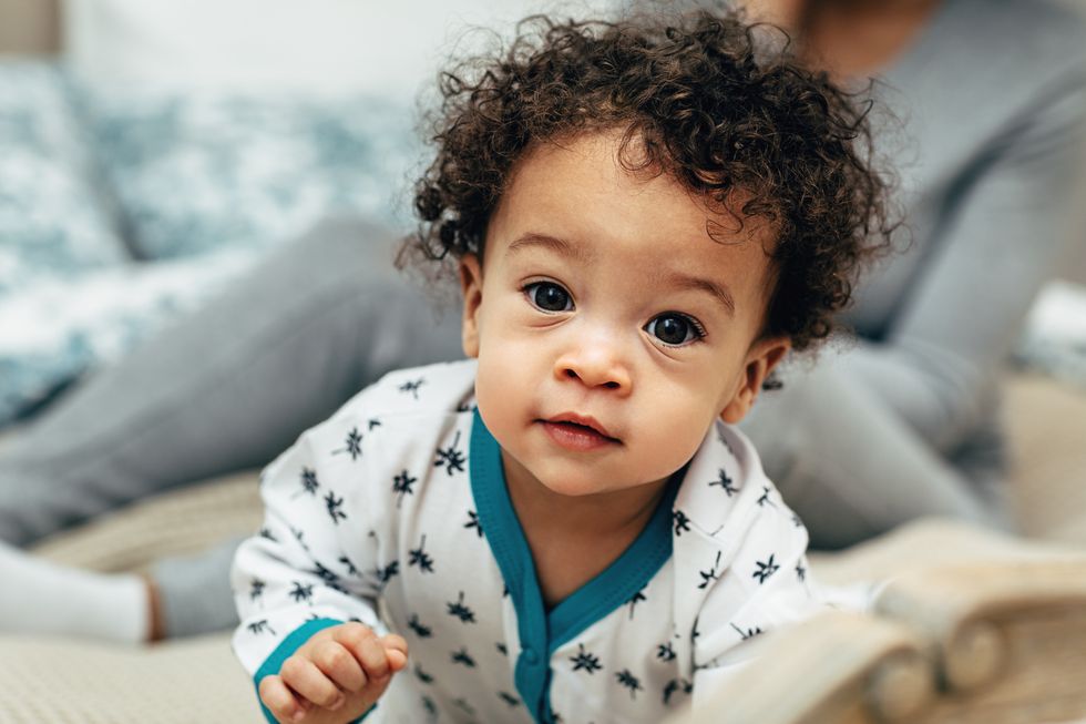 close up portrait of a baby boy crawling on bed