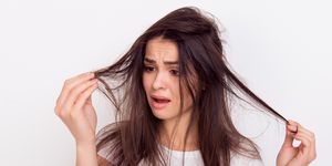 close up portrait of frustrated young brunette woman with messed hair on white background