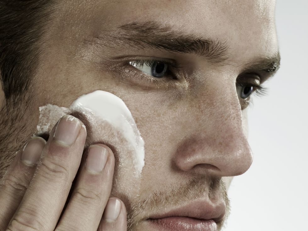 closeup portrait of man applying moisturizer