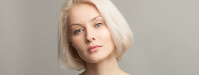 close up portrait of young beautiful blonde woman on gray