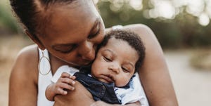 close up portrait of young mother holdiing infant daughter outside