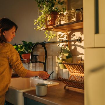 close up shot of a woman washing a frying pan with a cleaning liquid under tap water. using dishwasher in a modern kitchen. natural clean diet and healthy way of life concept.