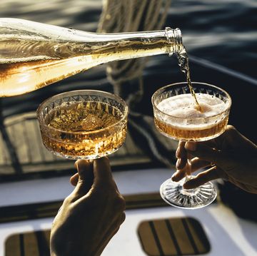 a close up shot of friends clinking sparkling wine glasses at sunset on a yacht