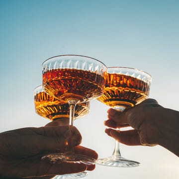 a close up shot of friends clinking sparkling wine glasses at sunset