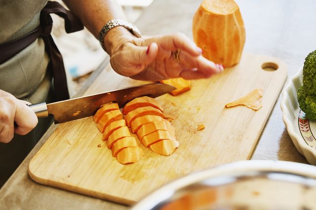 close up shot of woman chopping sweet potatoes during cooking class