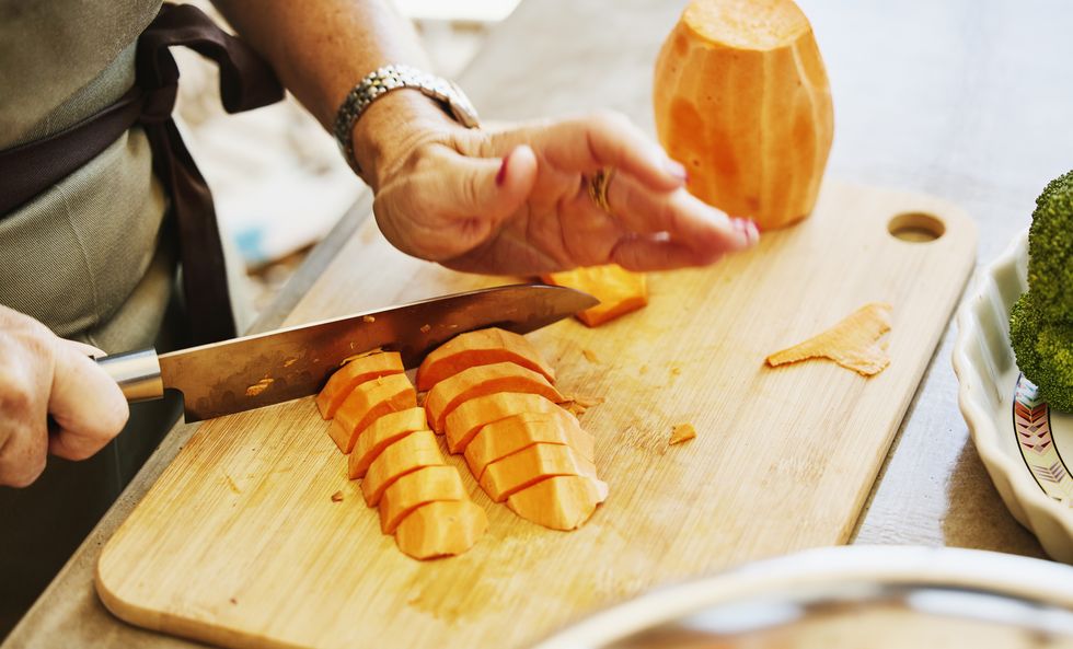 close up shot of woman chopping sweet potatoes during cooking class