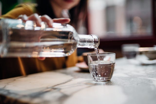 close up shot of woman pouring water into glass at restaurant