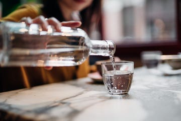 close up shot of woman pouring water into glass at restaurant