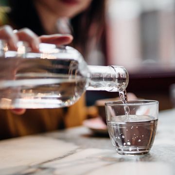 close up shot of woman pouring water into glass at restaurant