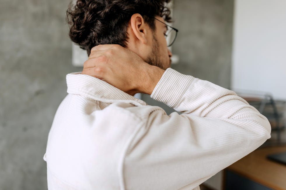 close up shot of young man experiencing neck pain at home office