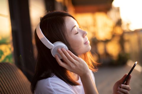 close up shot of young woman enjoying music over headphones and using smart phone