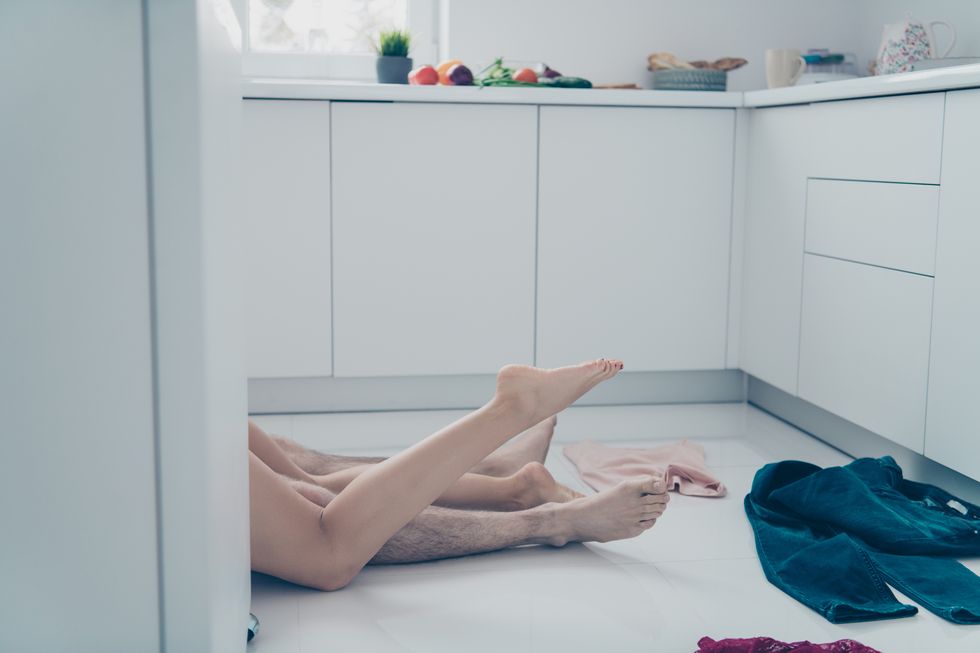 close up side profile view photo two people legs hips without clothes pair she her lady lying on he him his behind kitchen furniture prelude process white floor outfit chaos can not wait go bedroom
