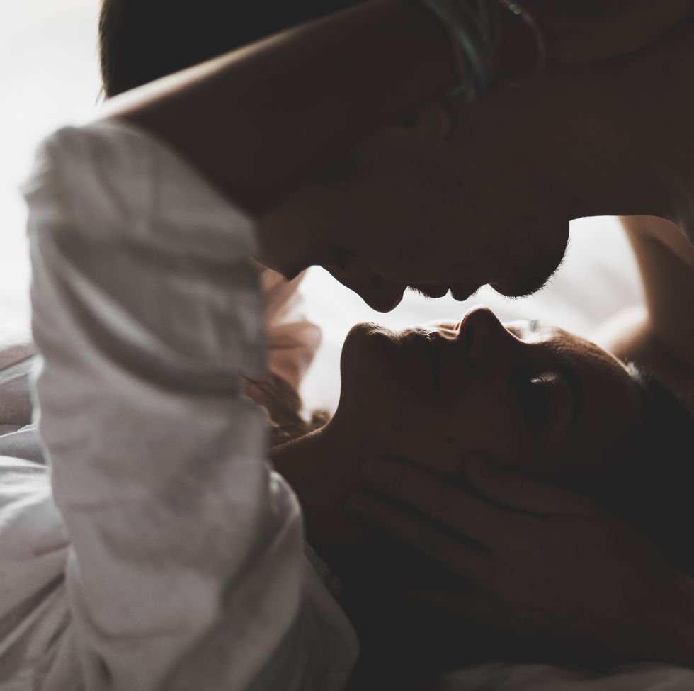 close up silhouette of couple kissing with love and passion in bed