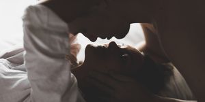 close up silhouette of couple kissing with love and passion in bed