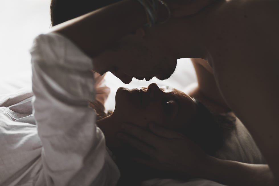 close up silhouette of couple kissing with love and passion in bed